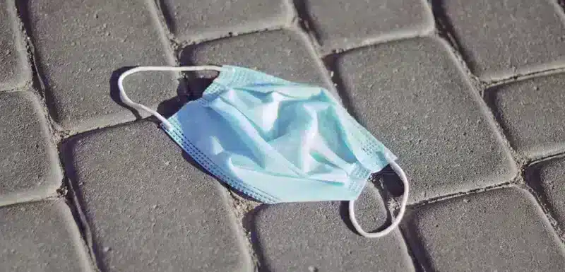 Disposable blue face mask lying discarded on the ground