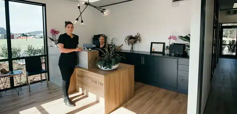 Smiling woman dentist standing in front of a dental clinic reception