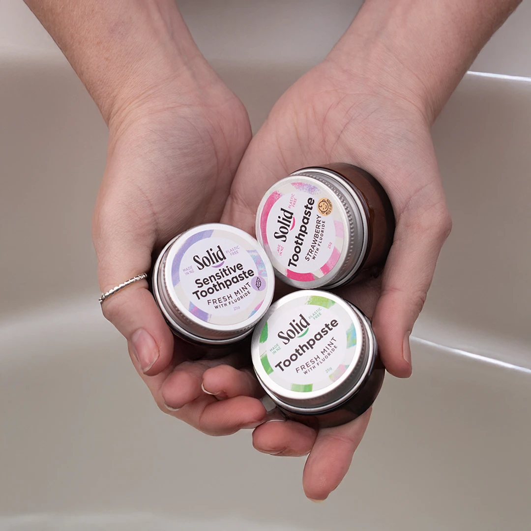 Hands holding three mini toothpastes